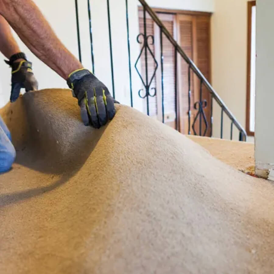 A man removing carpeting inside a home