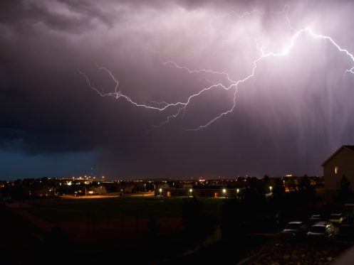 Lightning in the sky. The sky is cloudy, dark, and has a purple tone to it.