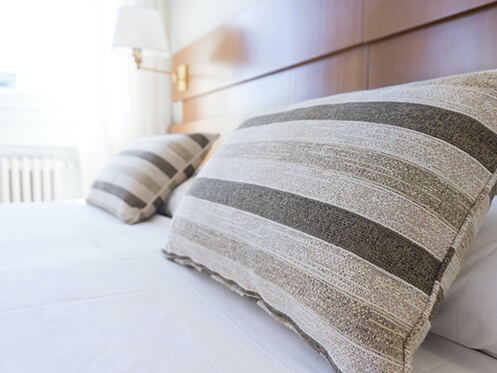 White bed with two brown and tan striped pillows