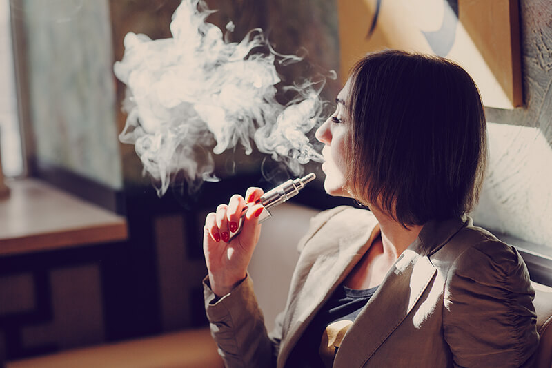 Woman smoking an e-cigarette in a home