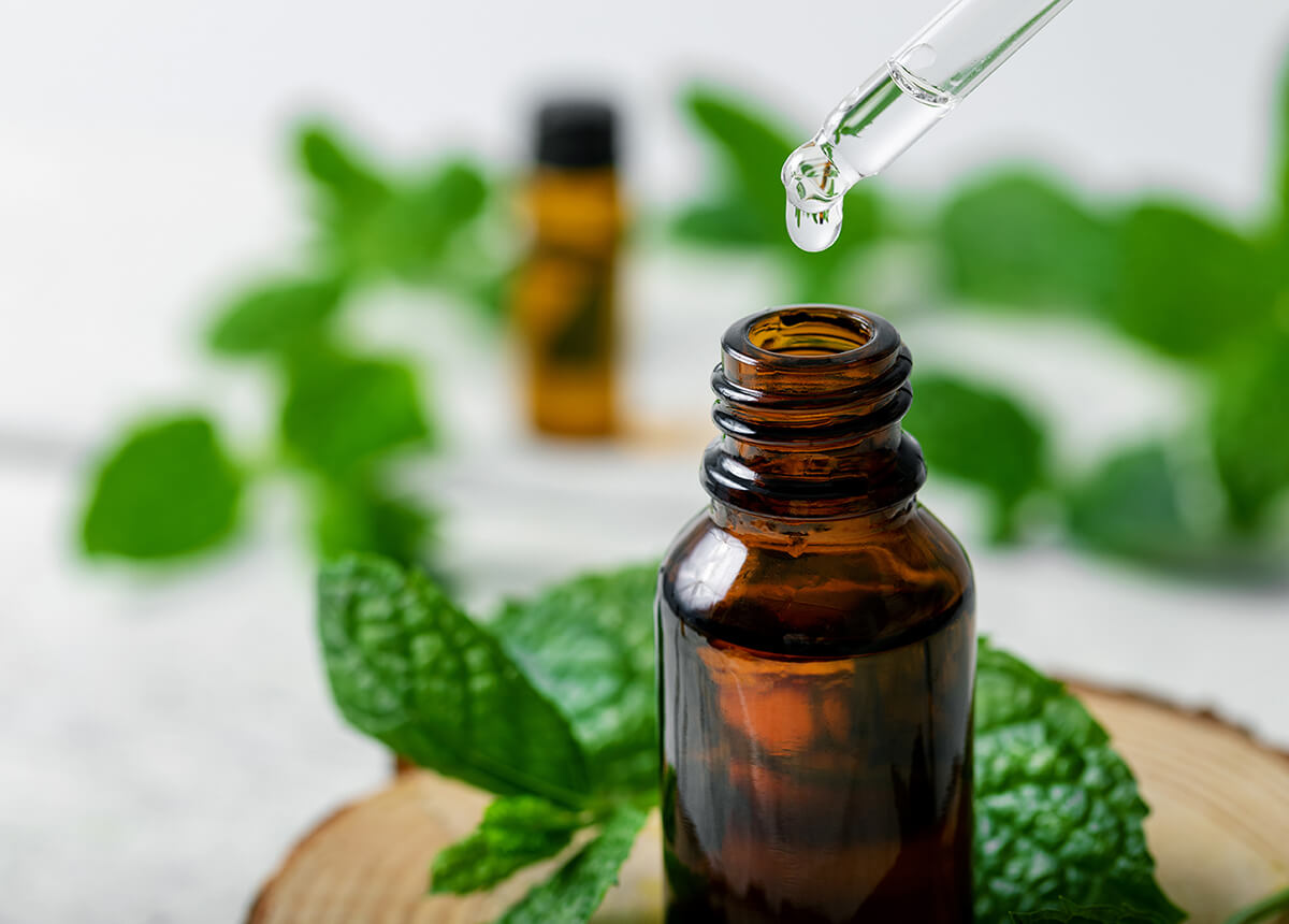 Essential oil bottle with mint leaves around it