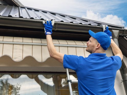 A technician inspecting the gutters of a home