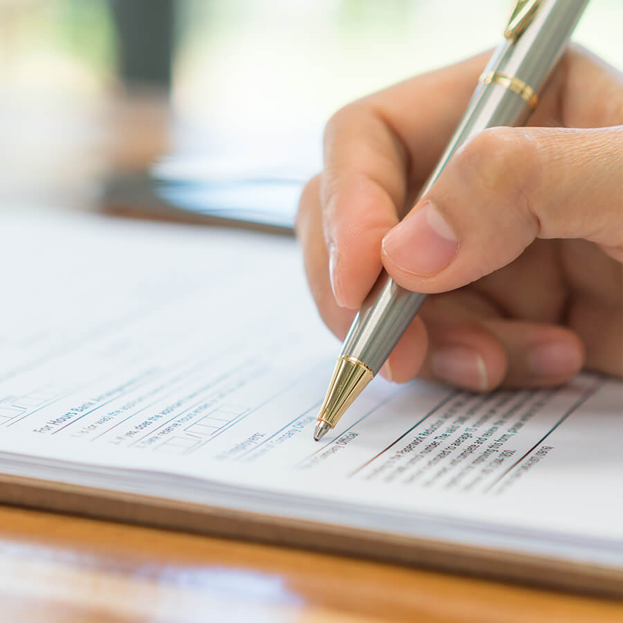 Closeup of a hand holding a pen and signing a document